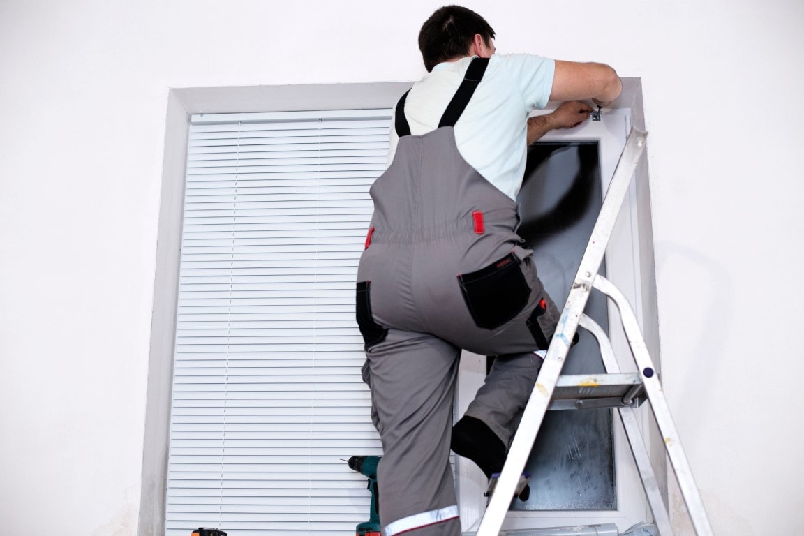 An image of a man working on a storm shutter